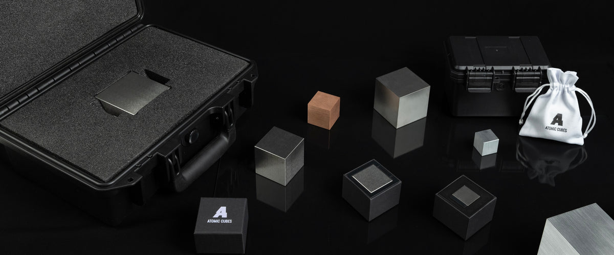 A precision-machined tungsten cube displayed in its protective presentation packaging.